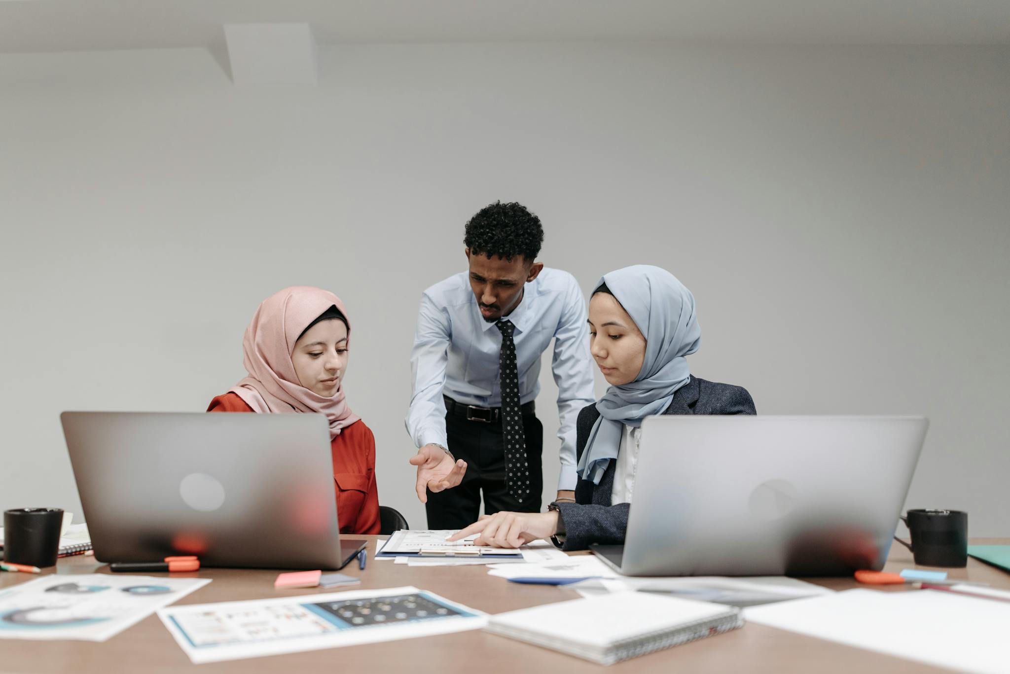 Colleagues discussing a project at a table with laptops, showcasing diversity and teamwork.